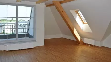 Dachzimmer mit großem Fenster und einem Holzbalken.