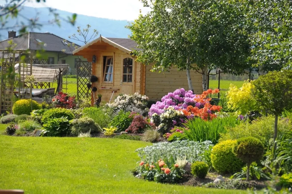 Gartenhaus aus Holz mit Blumenbeet im Vordergrund.