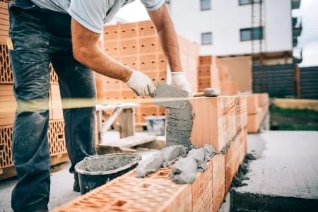 Bauarbeiter baut ein Haus mit Betonsteinen.