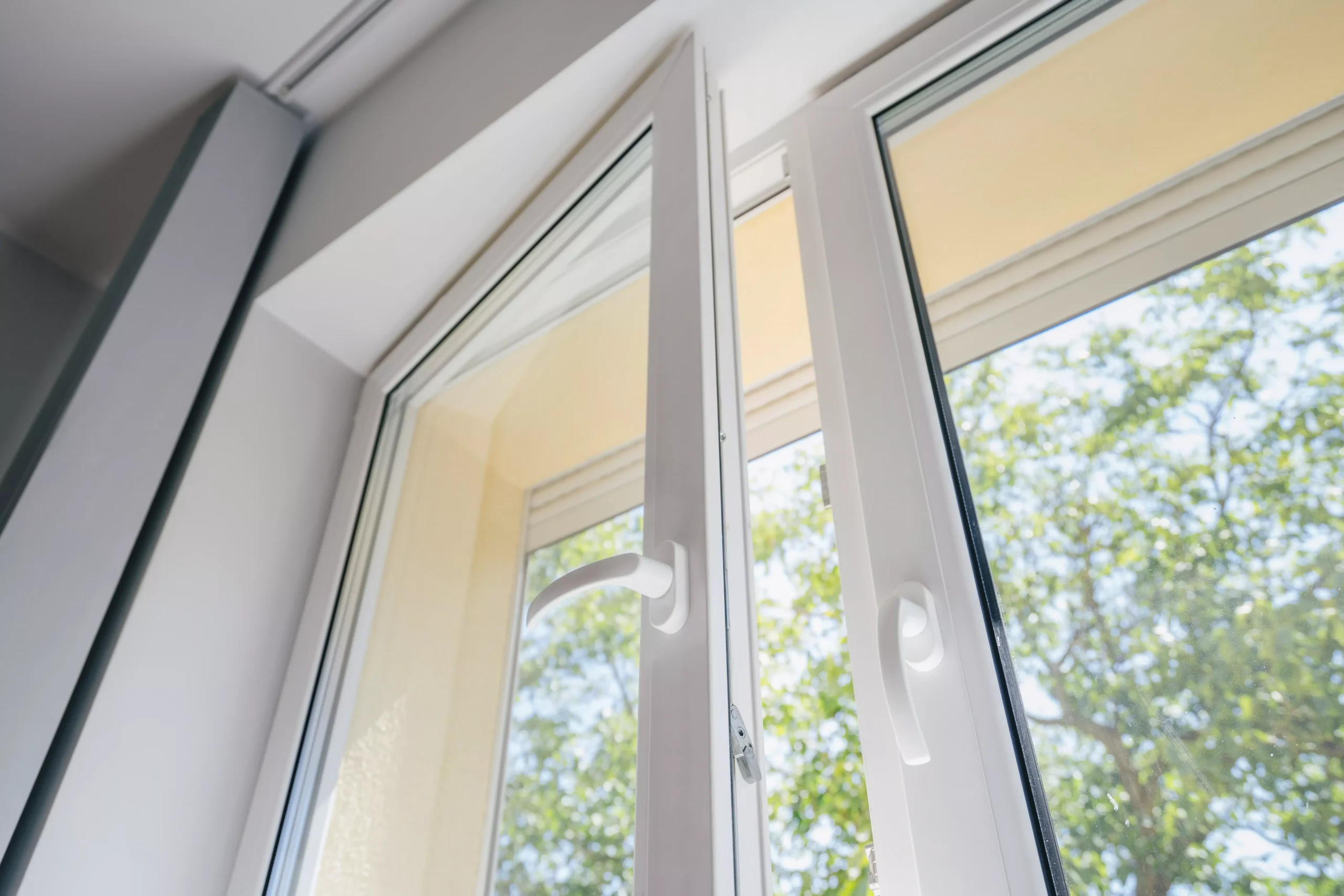 Weißes Kunststofffenster in Kippstellung mit Blick ins Grüne