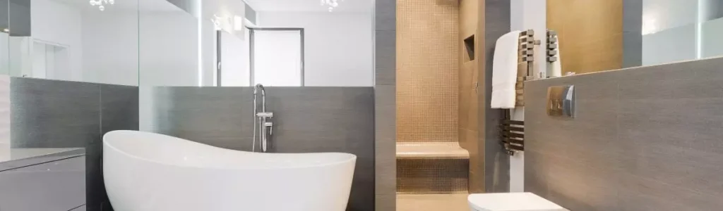 Badezimmer mit hellgrauen Fliesen und einer freistehenden Badewanne
